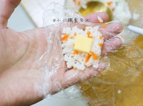 10、	取一小块饭，加入一块芝士，用保鲜膜包起来