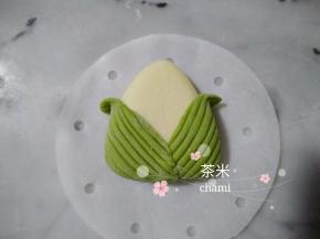 把两片叶子沾水后粘到三角白面团上，左边一片，右边一片，交叉着。