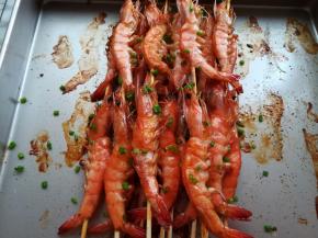 大虾烤熟后取出撒上适量的孜然粉和葱花