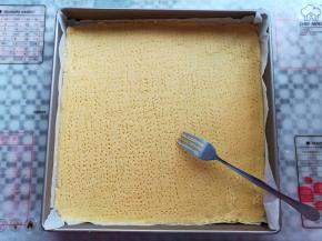 面团上下各铺一张油纸，用擀面杖把面团擀成薄片，用叉子在面团上扎孔，防止烘烤过程中面团受热不均匀翘起来