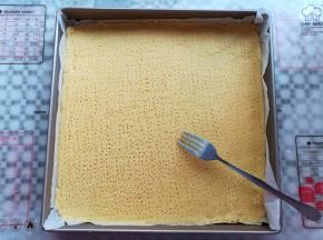面团上下各铺一张油纸，用擀面杖把面团擀成薄片，用叉子在面团上扎孔，防止烘烤过程中面团受热不均匀翘起来