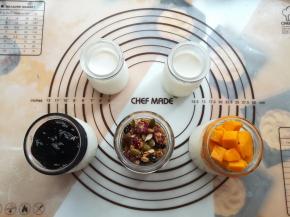 在酸奶杯里放上芒果肉，混合坚果，蓝莓果酱