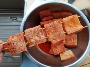 把腌好的冻豆腐用竹签串起来，每2根竹签串4块冻豆腐