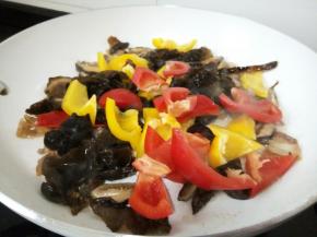 待香菇炒出香味，放黑木耳、青红椒，都是易熟的，可以一起下锅翻炒。