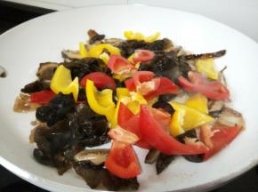 待香菇炒出香味，放黑木耳、青红椒，都是易熟的，可以一起下锅翻炒。