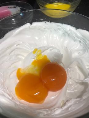 蛋白霜打发至有阻力和有清晰纹路不易消失的湿性发泡时，加入蛋黄继续中速打发。
