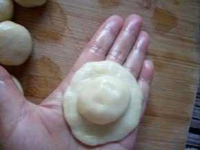 取一个水油面按扁，包住油酥面，收口捏紧。