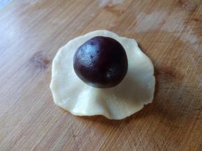 擀成中间厚，边缘薄的面皮，包裹上包了蛋黄的豆沙馅。