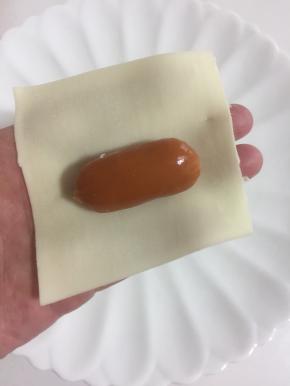 取一张饺子皮，把小脆皮肠放在中间。