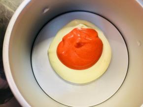 将混合好的蛋糊，分成两部分。其中一部分加入红丝绒精华，颜色随自己喜欢而定。用同样大小的两个勺子，取原色蛋糊放置与模具中间位置，再区一勺红色蛋糊放置与原色蛋糊之上。以此类推。