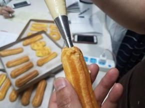 烤制好的泡芙，放凉，我们可以利用这个长长的花嘴，把卡仕达酱直接挤进去。