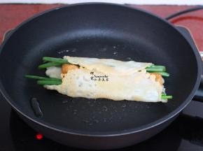 把油条、香葱卷起来，并且用锅铲压紧实；