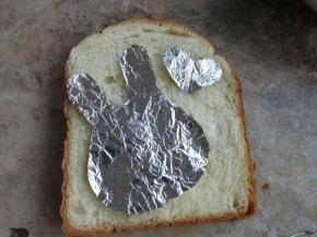 把锡纸剪成兔子形状和小的心形，贴在吐司表面