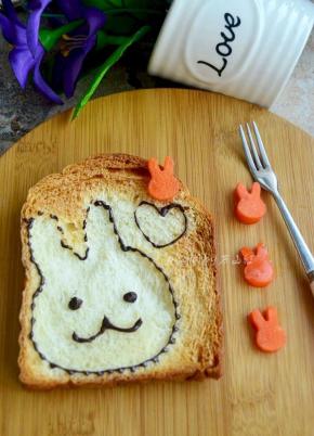 用巧克力勾勒出兔子轮廓，点上眼睛和嘴巴，心型也勾勒出来，萌萌哒爱心小兔吐司片就做好啦，哄小孩很有效果的哦