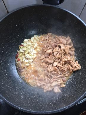 把煸炒好的肉片拨到一边，放入蒜瓣，生姜，干辣椒，花椒爆香。