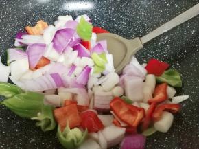 开火，利用锅里的余油倒入洋葱，青红辣椒，手指年糕翻炒二分钟