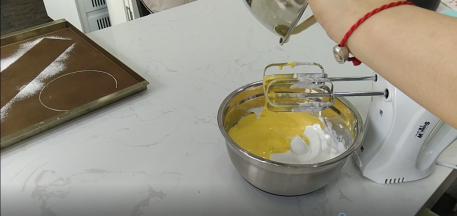 5.蛋黄打发泛白后加入蛋白中，继续高速打发