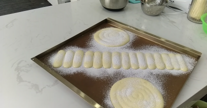 8.在烤盘上挤好之后，筛上糖粉。如果很快糖粉就被面糊吸收就再筛一层。然后放入预热好的烤箱，200℃烘烤15分钟左右至颜色金黄。