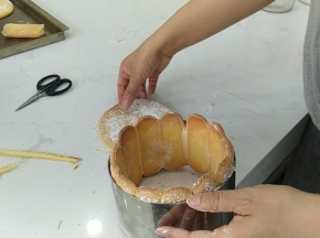 9.小心的将手指饼干脱模后摆入模具中裁去多余部分，圆形的蛋糕片裁剪的比慕斯圈/活底模具略小一些的尺寸，确保可以放入手指饼干围圈中。