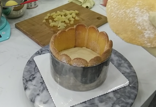 16.倒入铺好蛋糕底和手指饼干围边的模具中约一半高度，再铺上另外一片海绵蛋糕片