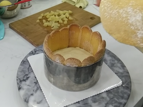 16.倒入铺好蛋糕底和手指饼干围边的模具中约一半高度，再铺上另外一片海绵蛋糕片