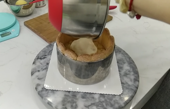 17.先铺上切成小块的白桃块，然后倒入剩余的巴巴露亚馅，用刮刀推平表面后放入冰箱冷藏