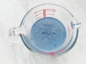 先来做奶冻。取150克温热的蝶豆花牛奶（不要超过60度），加入细砂糖，再加入泡好的挤干水份的吉利丁片，慢慢搅拌至吉利丁片完全融化。