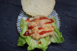 再放上生菜叶和鸡排，挤上番茄酱，加上芝士片和番茄片后盖好