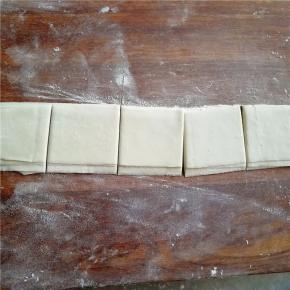 将每条展开叠起，然后切成馄饨皮