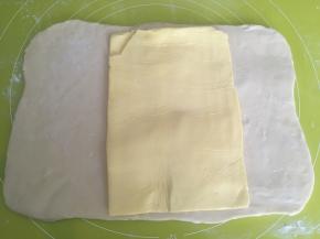 取出冷冻的黄油片，用剪刀裁掉保鲜袋，将黄油铺在面片中间，一起室温回下温，面片变软，可以对折即可