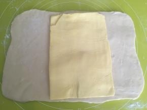 取出冷冻的黄油片，用剪刀裁掉保鲜袋，将黄油铺在面片中间，一起室温回下温，面片变软，可以对折即可