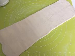 揉面垫上撒点干粉，用擀面杖从中间向两边擀开，将面片擀长，长度40多厘米