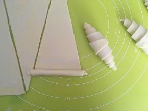 从三角形的宽处向三角尖卷起来，裁掉的边角也别丢掉，叠在一起卷起来