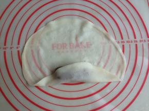 将春卷皮的一端向上折，包裹住豆沙馅
