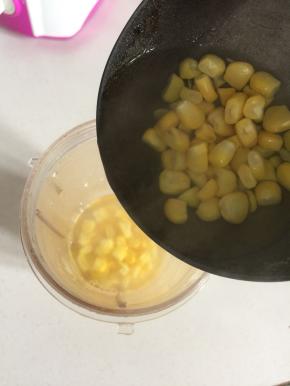 煮好的甜玉米粒连同汤汁儿一起装进料理机的果汁杯中。