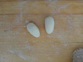 取5克白面团分成两份，揉成椭圆形，用来做胳膊