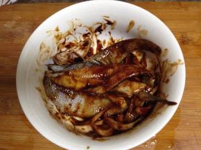 取另一小碗加入剩下的洋葱丝和姜片加入海鲜酱、烧烤酱、鱼柳拌匀腌10分钟