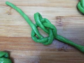 在把豆角的一端从上穿过，另一条从下穿过