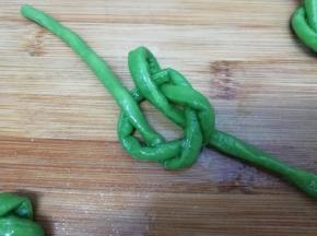 在把豆角的一端从上穿过，另一条从下穿过