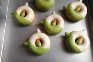 接着把先前表面凝固的甜甜圈，再放入到抹茶巧克力中，沾上1/3的抹茶巧克力，沾完后继续放置表面凝固。最后再用黑巧克力笔画上猫咪的眼睛，鼻子和胡须就ok啦！