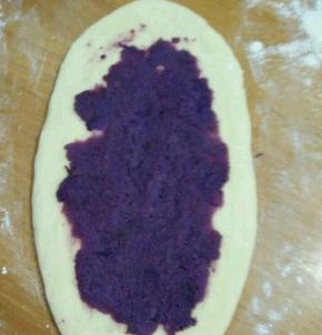 把饧好的面团檊成长舌状，放适量紫薯泥，压平。