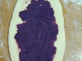 把饧好的面团檊成长舌状，放适量紫薯泥，压平。