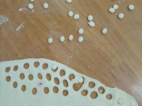 白色面团擀成薄片，压出小圆形。