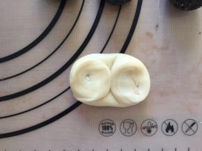 松弛好的面团，卷口朝上从中间对折，对折好的面团向下压扁