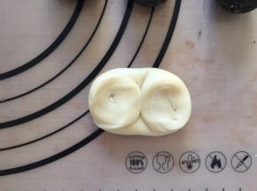 松弛好的面团，卷口朝上从中间对折，对折好的面团向下压扁