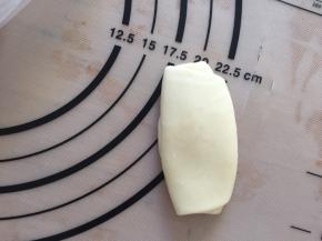 松弛好的面团竖着放，轻轻压一下，再擀成长舌状，从上向下卷起