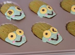 绿色巧克力挤入玛德琳上，带稍微凝固放上眼睛，黑色巧克力画嘴巴，粉色巧克力画表情，然后放入冰箱冷藏10分钟即可