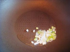 不粘锅里倒入适量的食用油，倒入葱翻炒煸香。