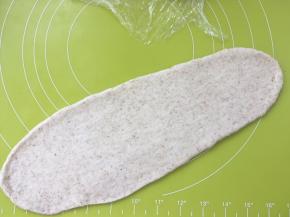 取一份松弛好的面团，用擀面杖擀成长条，松弛好的面团擀的时候有轻微回弹，回弹过大证明面团没松弛好