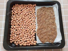 将花生仁和亚麻籽平铺在烤盘里